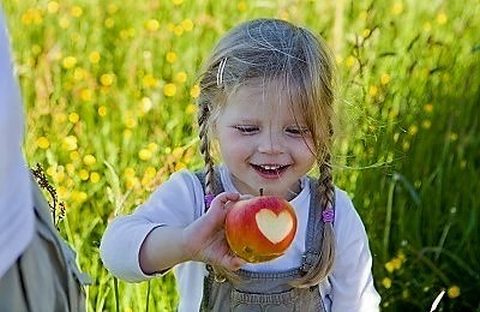 Auf dem Foto beißt ein kleines Mädchen in eine Apfel.